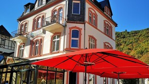 A traditional European-style building with a balcony and a red umbrella. - Haus Hohenzollern (Bad Bertrich)