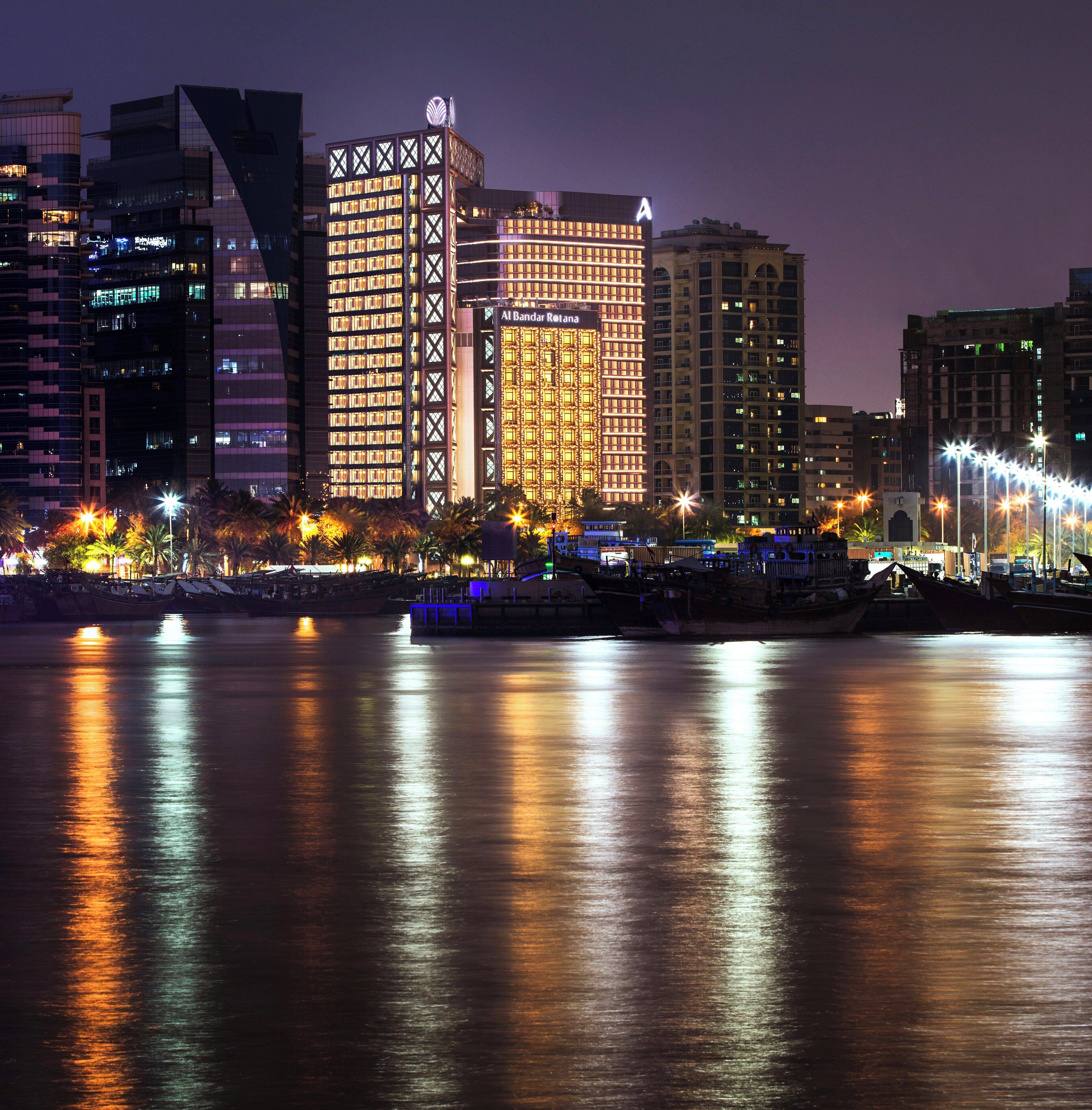 A cityscape with modern buildings, a river, and boats.