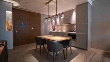 A modern kitchen with a dining area, featuring a wooden table, chairs, and pendant lights.