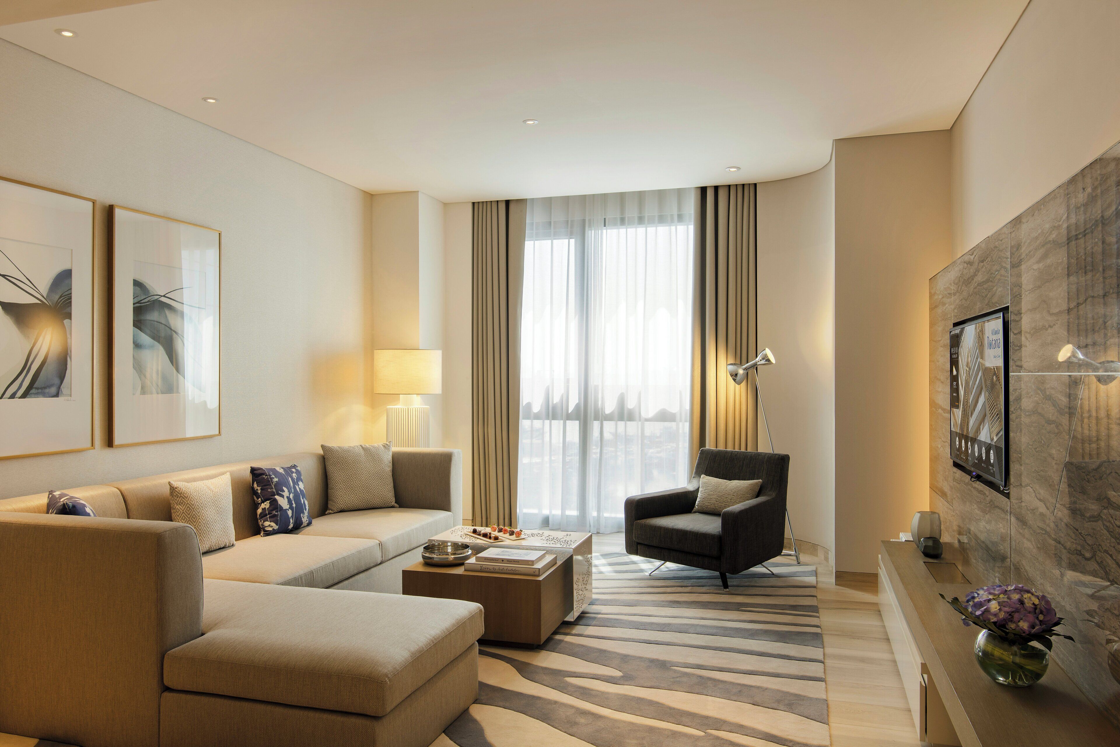 A modern living room with a sofa, armchair, coffee table, and artwork on the walls.