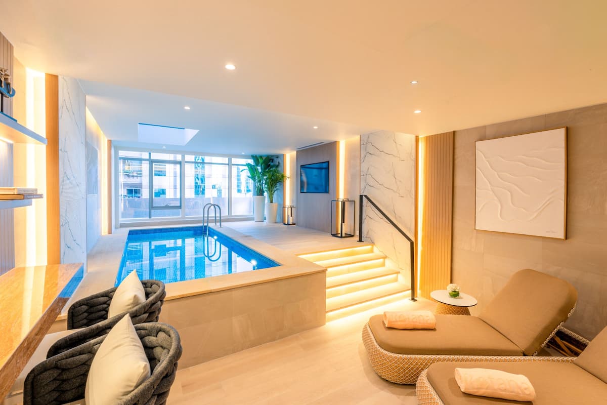 Un intérieur moderne avec une piscine, un espace salon et un escalier menant à un balcon.