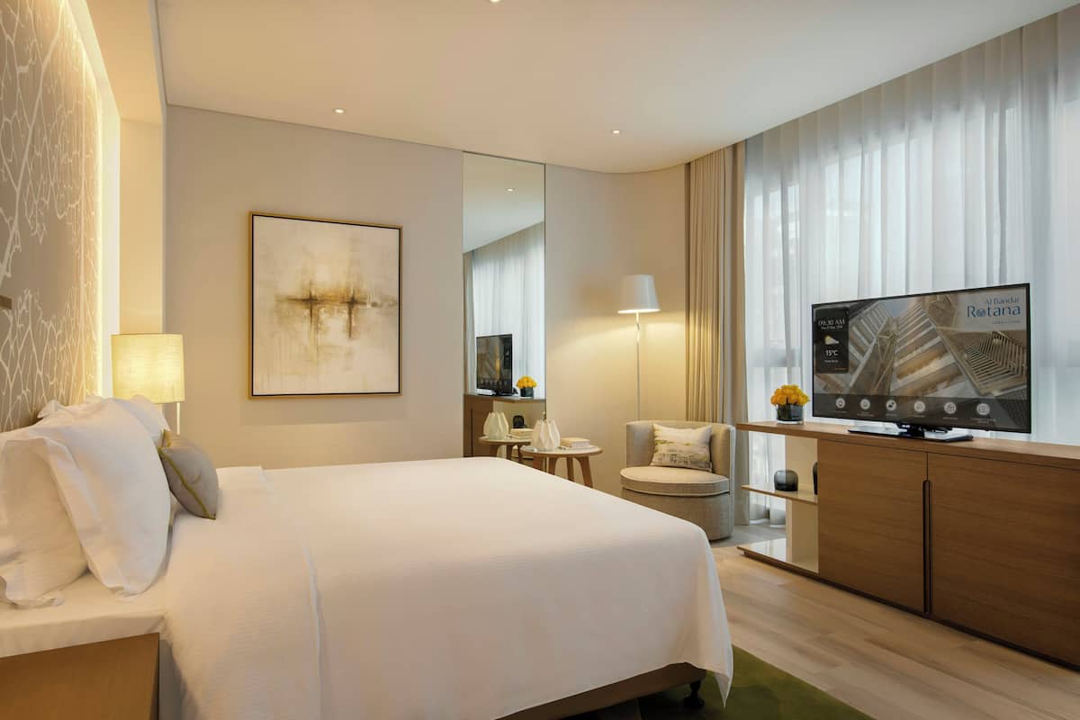 Une chambre d’hôtel avec un grand lit, une télévision, un bureau et une chaise.