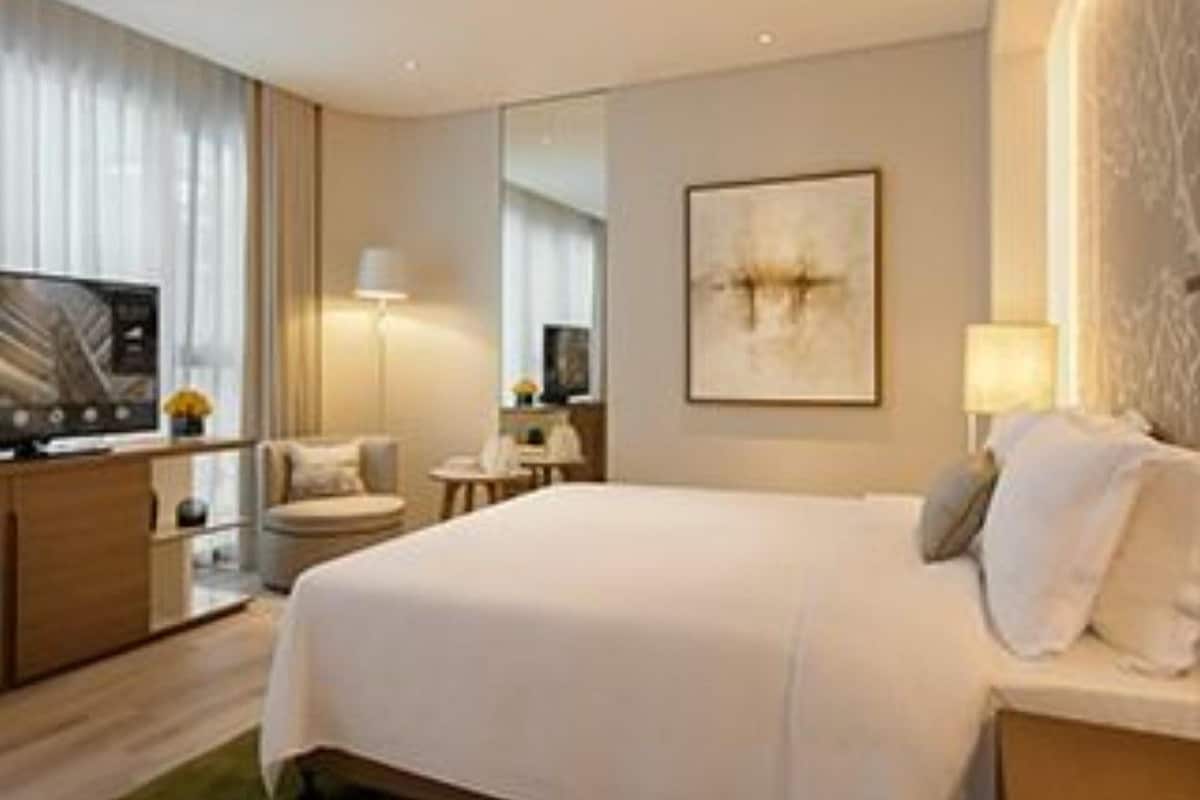 Una habitación de hotel con una cama, televisión, escritorio y una silla.