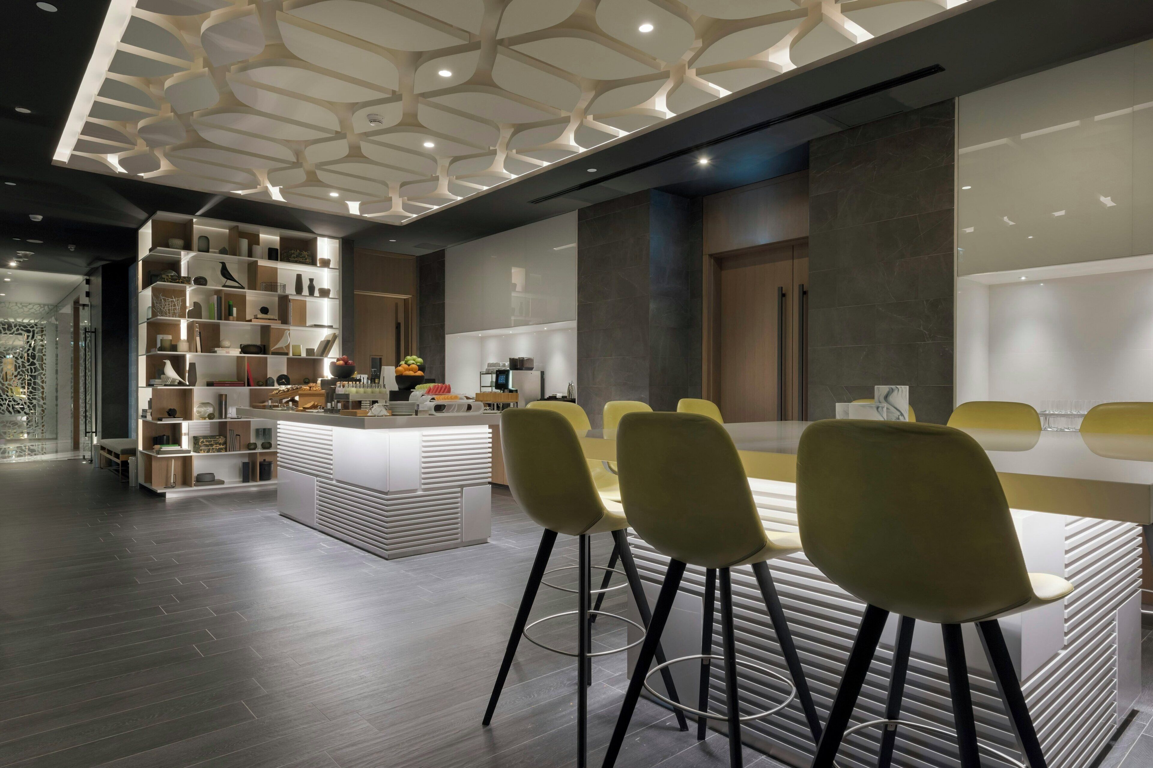 Una cocina moderna con una isla central, taburetes de bar y un techo decorativo.