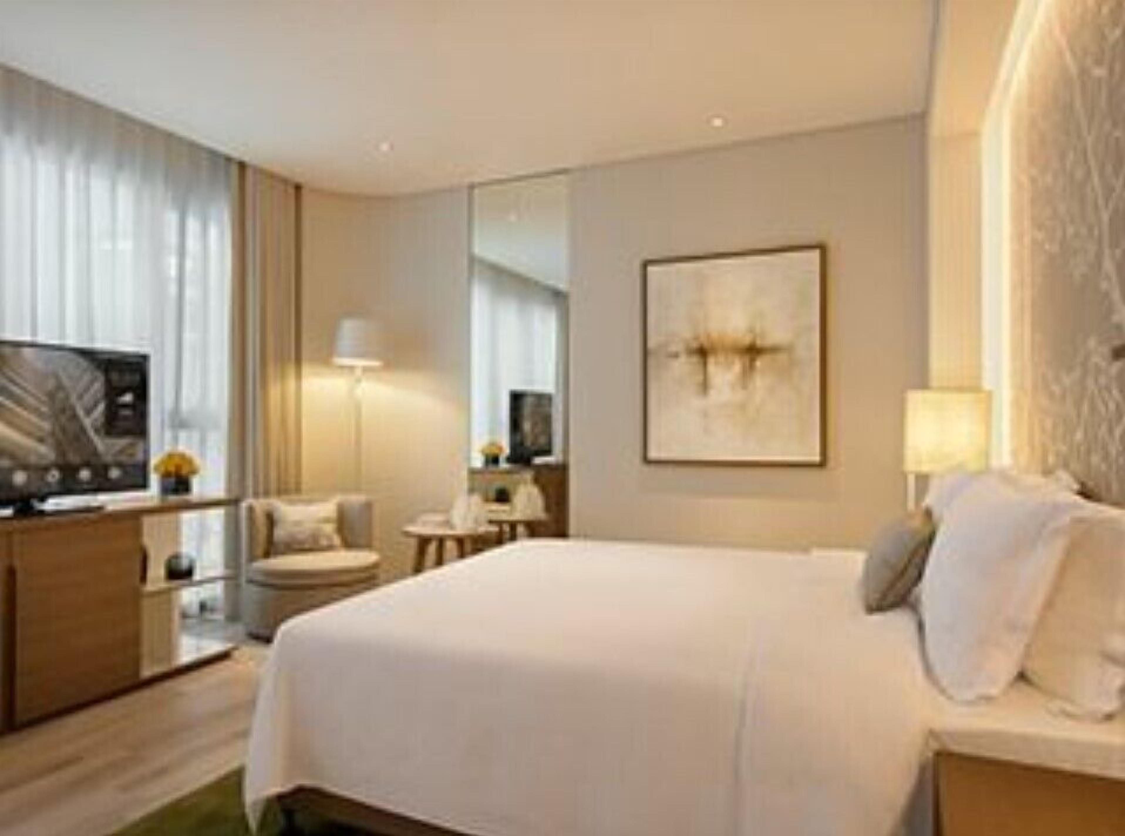 A hotel room with a bed, a television, a desk, and a chair.