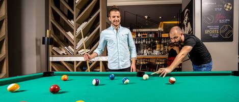 A pool table with balls, a person in a light blue shirt, and another in a black shirt.