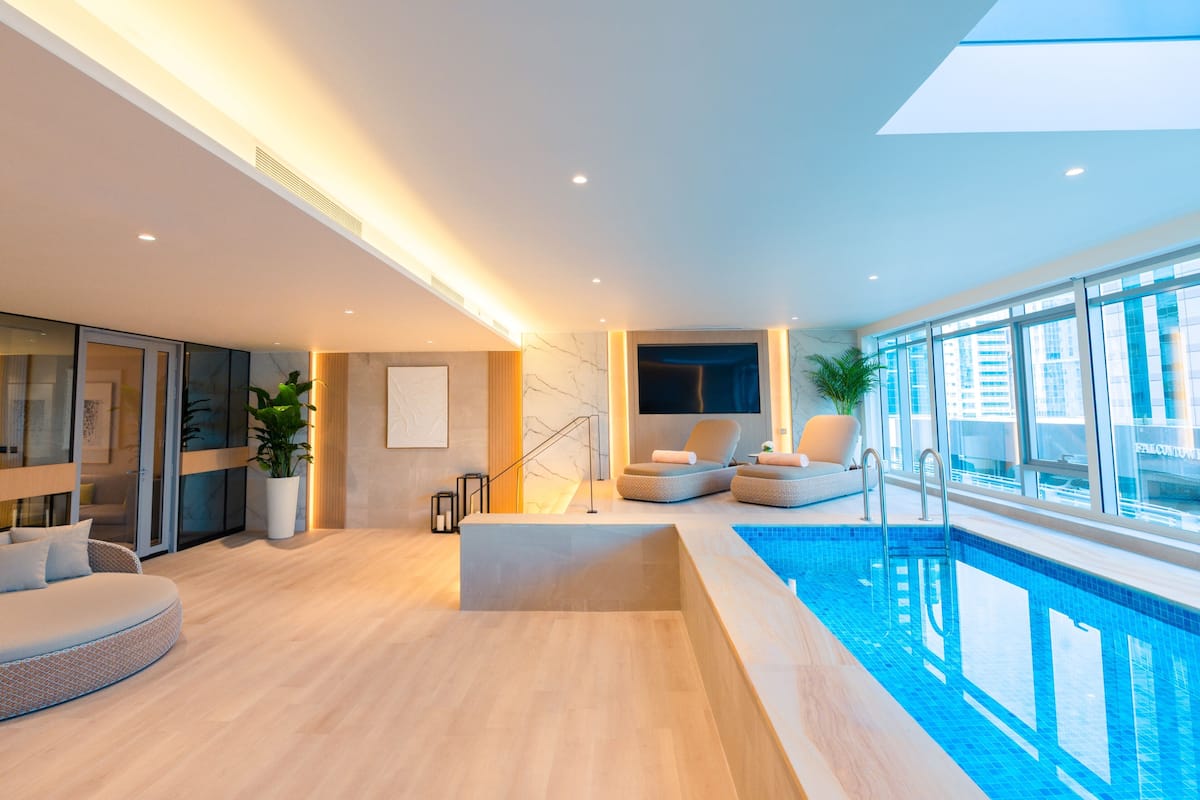 Un intérieur moderne avec une piscine, un espace salon et de grandes fenêtres.