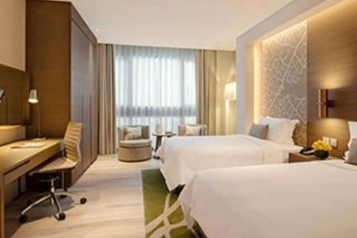 Une chambre d’hôtel avec deux lits, un bureau, une chaise et une vue sur l’extérieur.