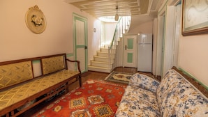 Une pièce comprenant un canapé, un banc et un tapis à motifs. Un escalier y mène à une autre pièce.