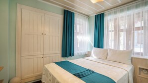 Une chambre à coucher avec un grand lit, une armoire et une fenêtre avec des rideaux.