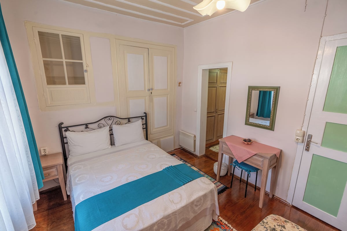 A bedroom with a bed, a desk, a chair, and a wardrobe.