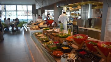 Un buffet proposant une variété de plats, avec un chef qui prépare les aliments en arrière-plan.