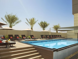 A swimming pool with lounge chairs and umbrellas, surrounded by palm trees.