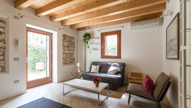 A living room with a wooden ceiling, a stone wall, a sofa, a coffee table, and a bench.