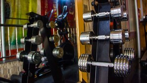 Une salle de sport équipée de divers appareils d’exercice, notamment des haltères et des machines de musculation.