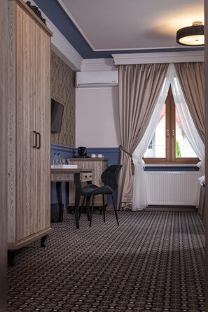 A room with a wooden wardrobe, a desk with a chair, a television, and a window with curtains. - Willa w Dolinie (Tarnow)