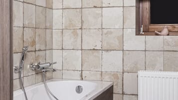 Ein Badezimmer mit Badewanne, einem Holzwaschtisch und einem gestreiften Boden.