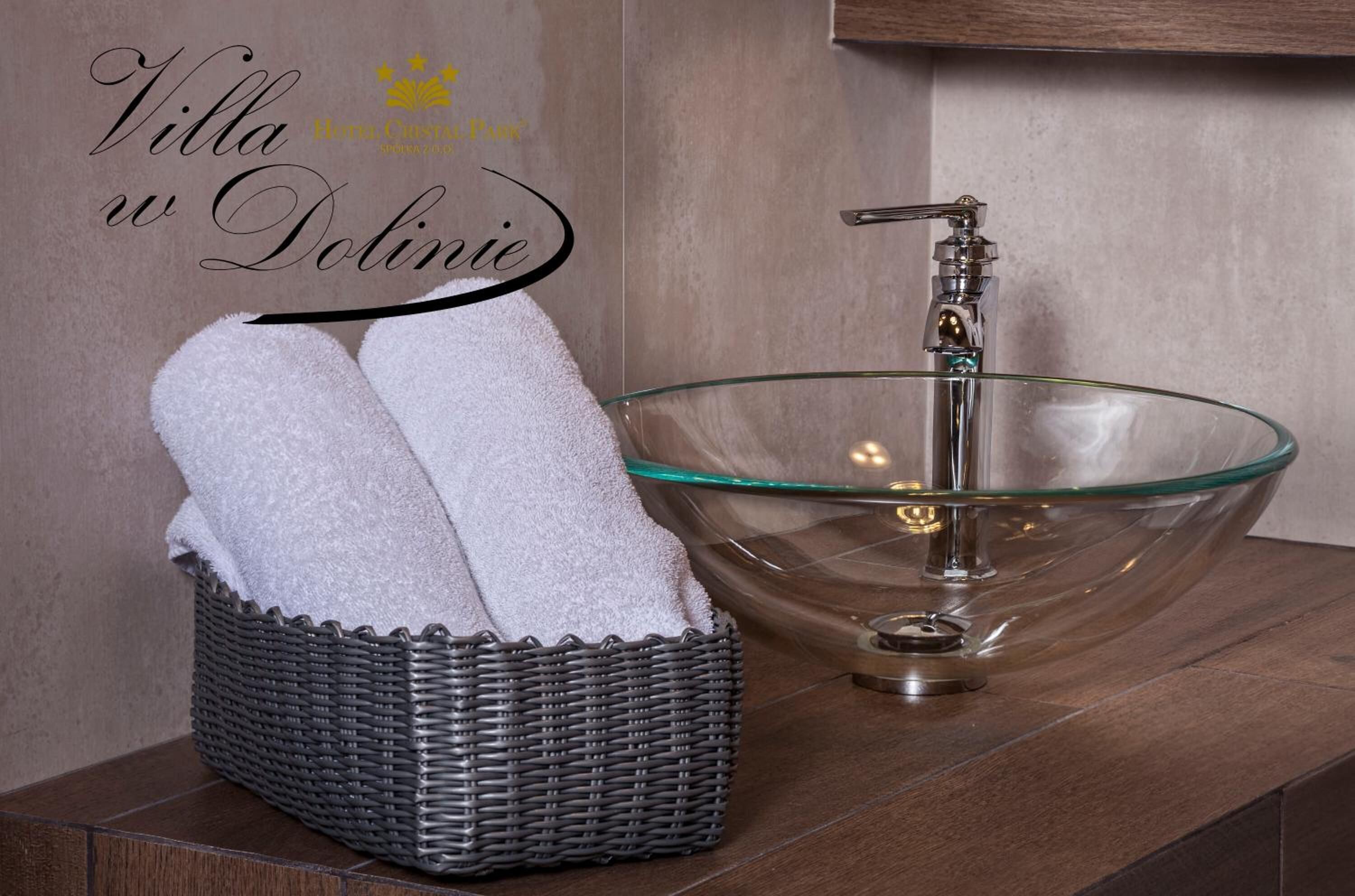 A bathroom with a glass bowl sink, a wicker basket with towels, and a wooden vanity.