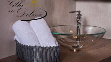 A bathroom with a glass bowl sink, a wicker basket with towels, and a wooden vanity.