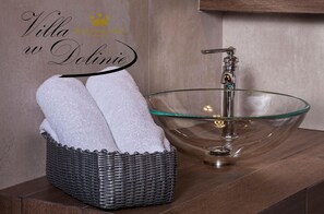 A bathroom with a glass bowl sink, a wicker basket with towels, and a wooden vanity. - Willa w Dolinie (Tarnow)
