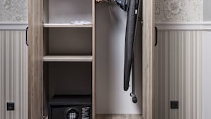 A wooden wardrobe with multiple shelves and a hanging rack, a black vacuum cleaner, and a black appliance on the bottom shelf. - Willa w Dolinie (Tarnow)