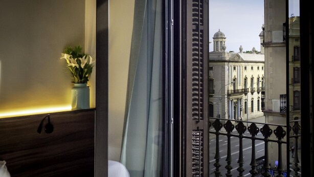 A hotel room with a view of a city street and a building with a dome. - Pensión Ciudadela (Barcelona)