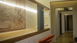A modern interior with a wooden bar counter, a map artwork, and an air conditioning unit. - Pensión Ciudadela (Barcelona)