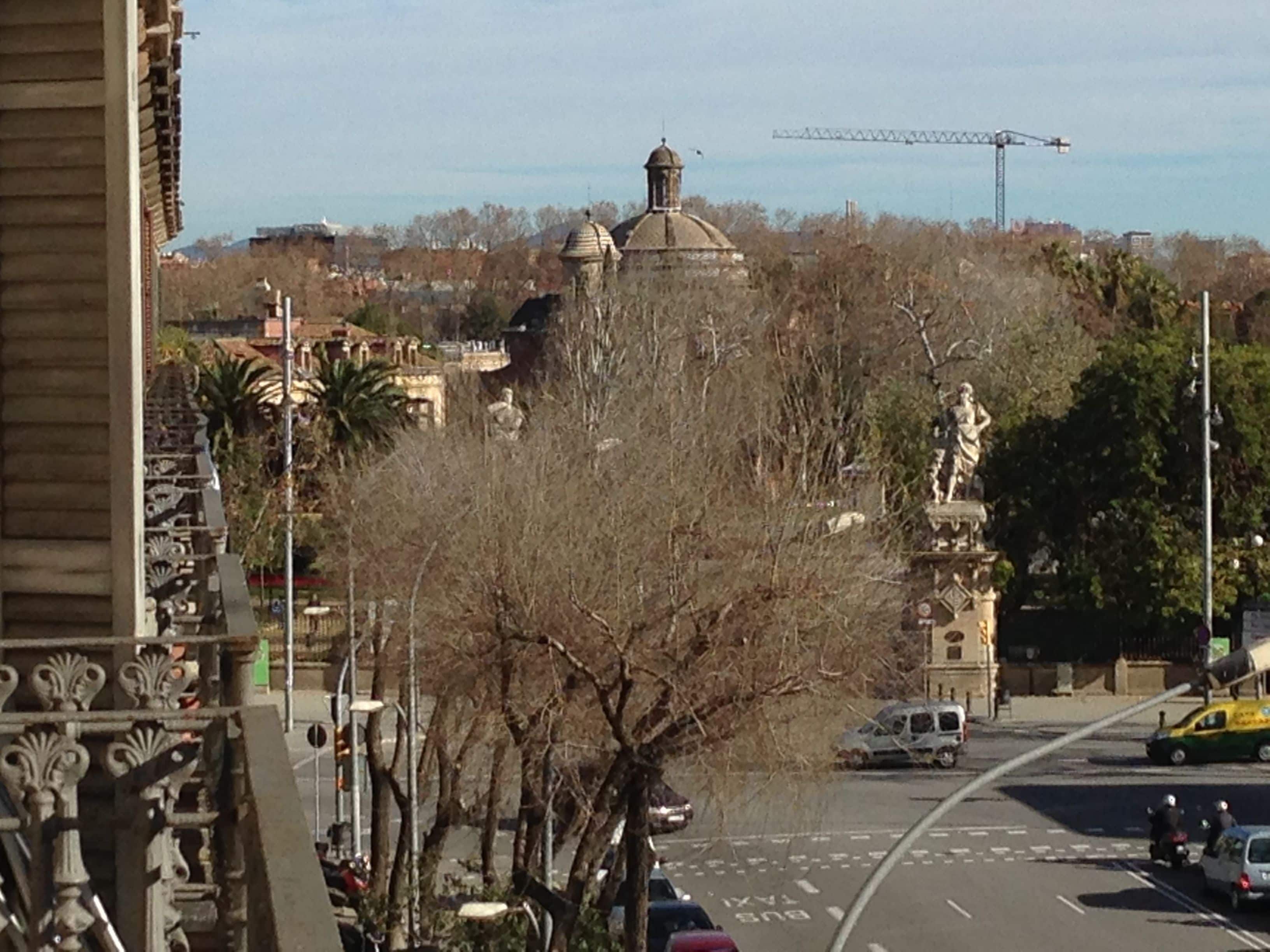 Vista de la calle con un edificio destacado que tiene una cúpula y una estatua.