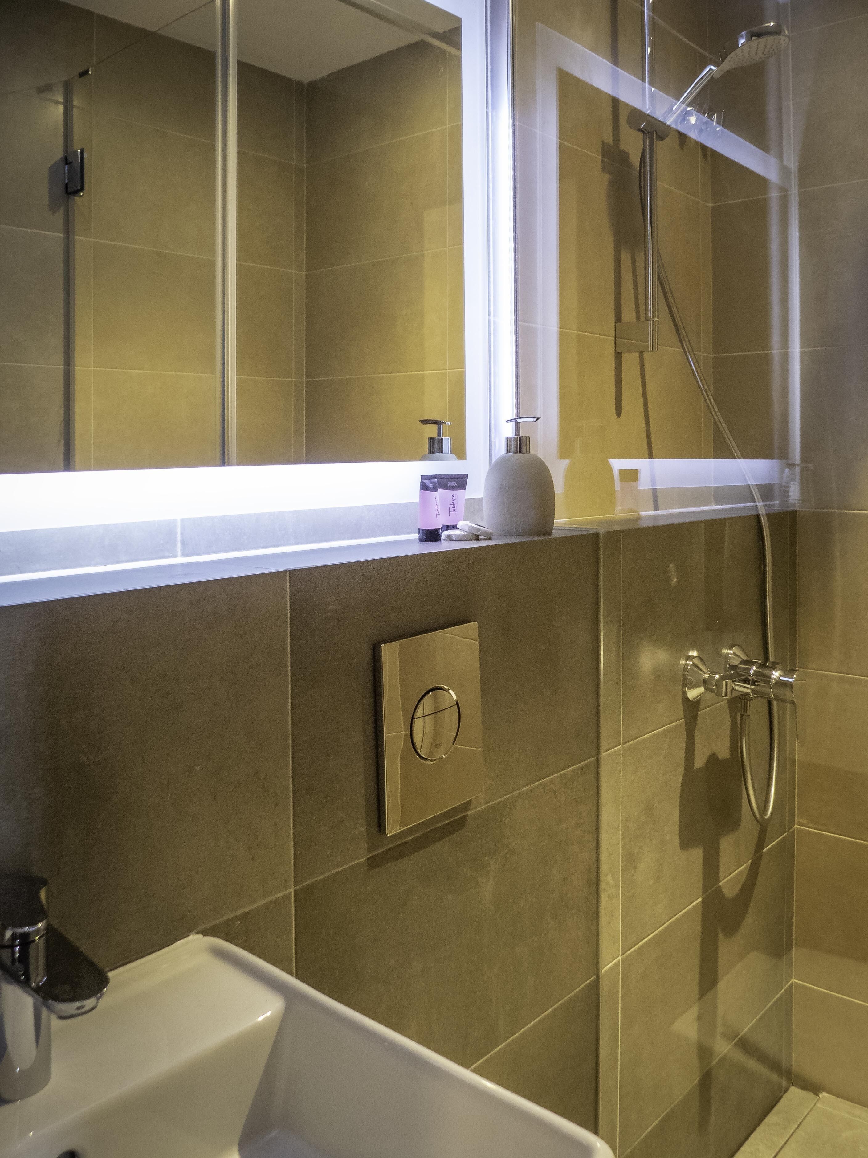 Ein modernes Badezimmer mit Dusche, Waschbecken und Spiegel.