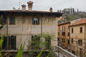 A historic building with a weathered facade, green shutters, and a visible mural. - Residenza Novecento (Verona)