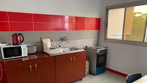 A compact kitchen with a microwave, toaster, sink, and gas stove. - Résidence Mbemba (Abidjan)
