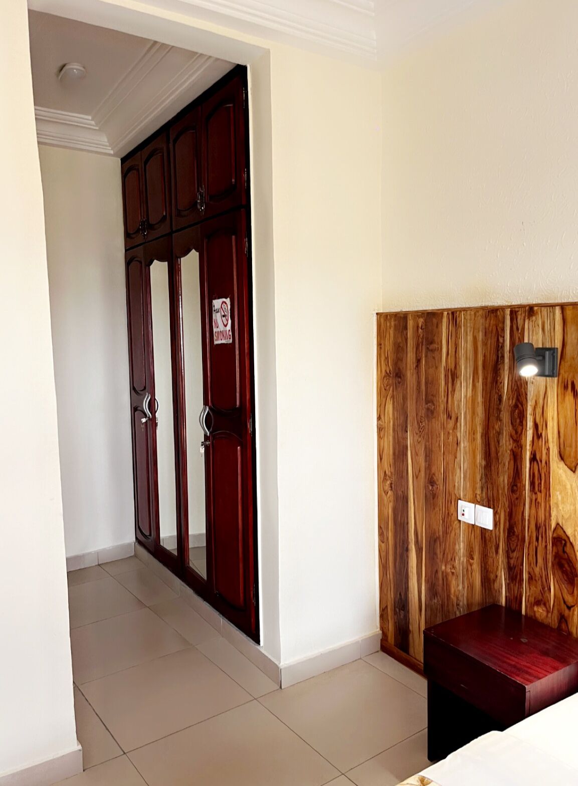 A hallway with a wooden door, a wall-mounted light fixture, and a small table.