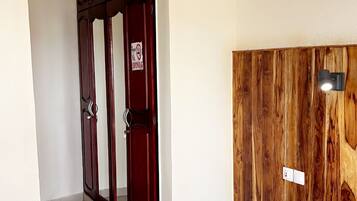 Un pasillo con una puerta de madera, una lámpara en la pared y una pequeña mesa.
