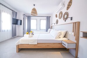 Moderni hotellihuone, jossa on suuri sänky, seinälle asennettu televisio ja puinen yöpöytä.