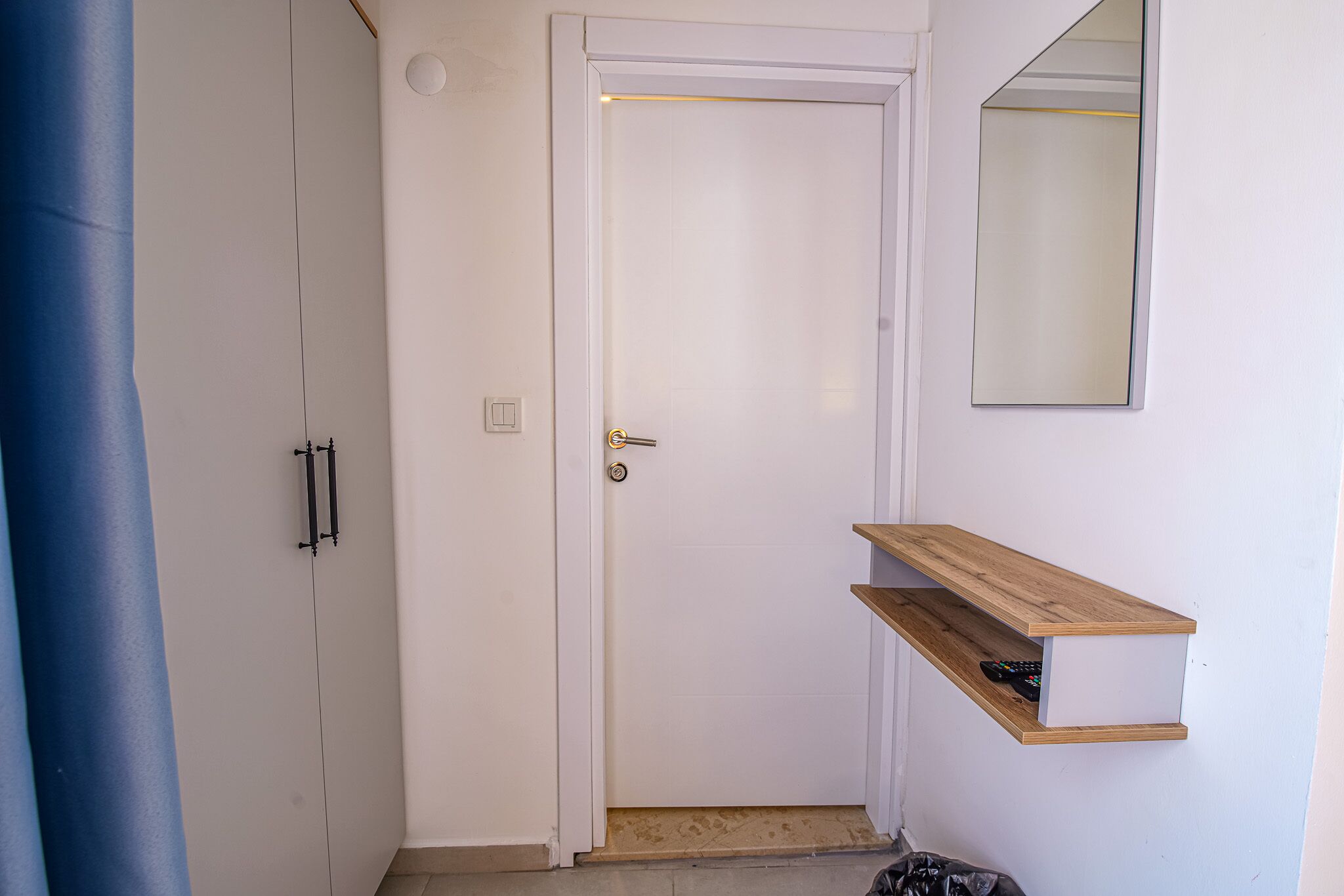 A white door with a small step leading to a wooden shelf.