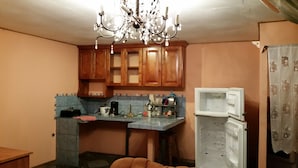 Una cocina con armarios de madera, salpicadero de azulejos, una lámpara de araña y un refrigerador.
