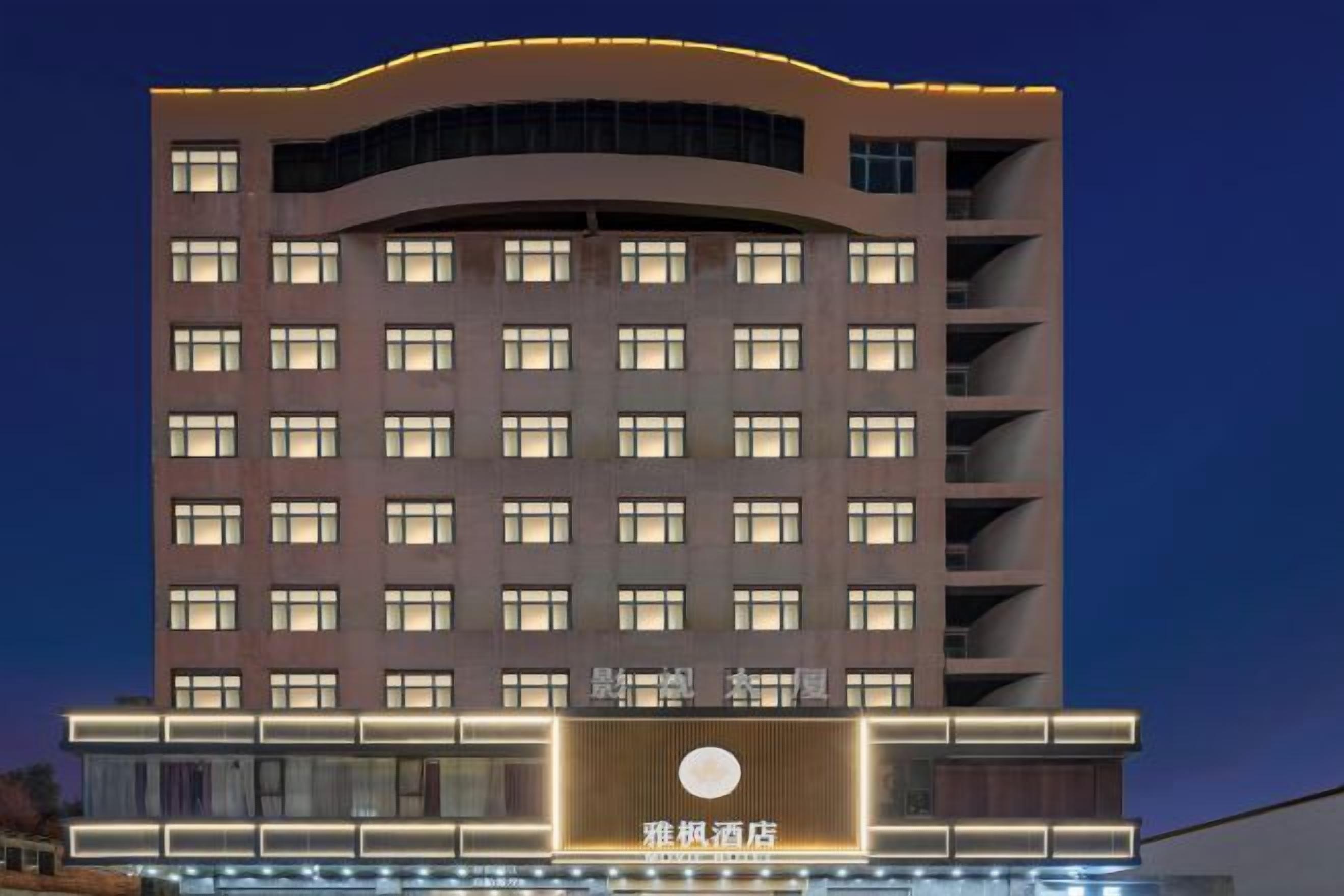 A multi-story hotel with a modern design, featuring a prominent entrance with a circular logo and illuminated signage.