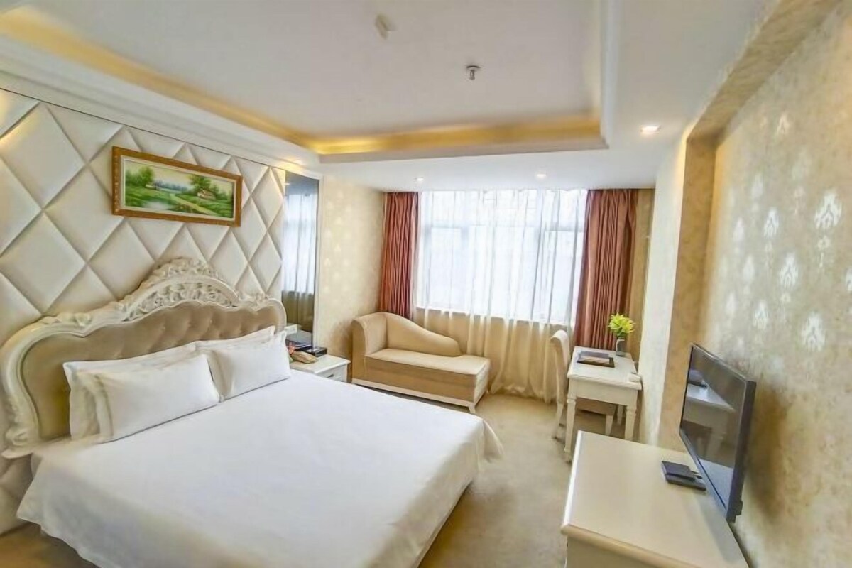 Ein Hotelzimmer mit einem großen Bett, einer Couch, einem Fernseher und einem kleinen Tisch.