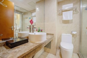 Ein Badezimmer mit Marmorplatte, zwei Waschbecken, einer Toilette und einer Duschkabine aus Glas.