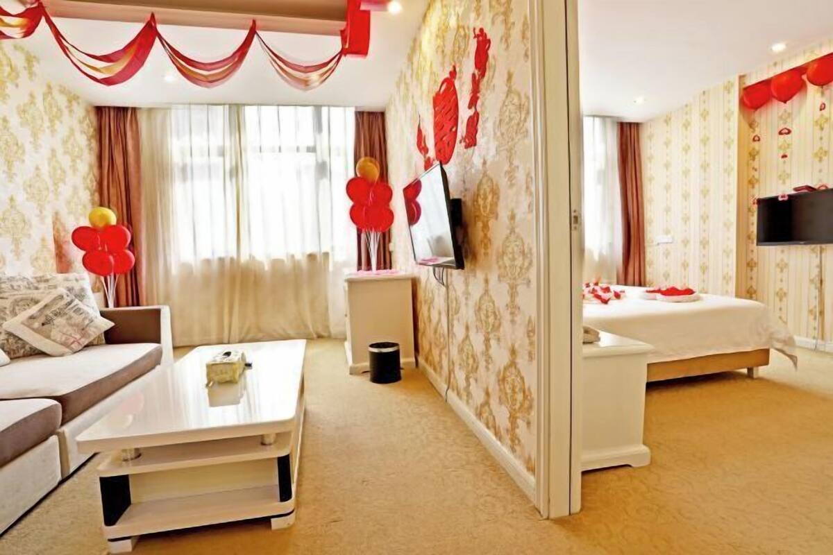A modern hotel room with a sofa, a coffee table, a TV, and a bed.