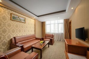 Ein Hotelzimmer mit einer Sitzecke, einem Couchtisch, einem Fernseher und einem Bild an der Wand.