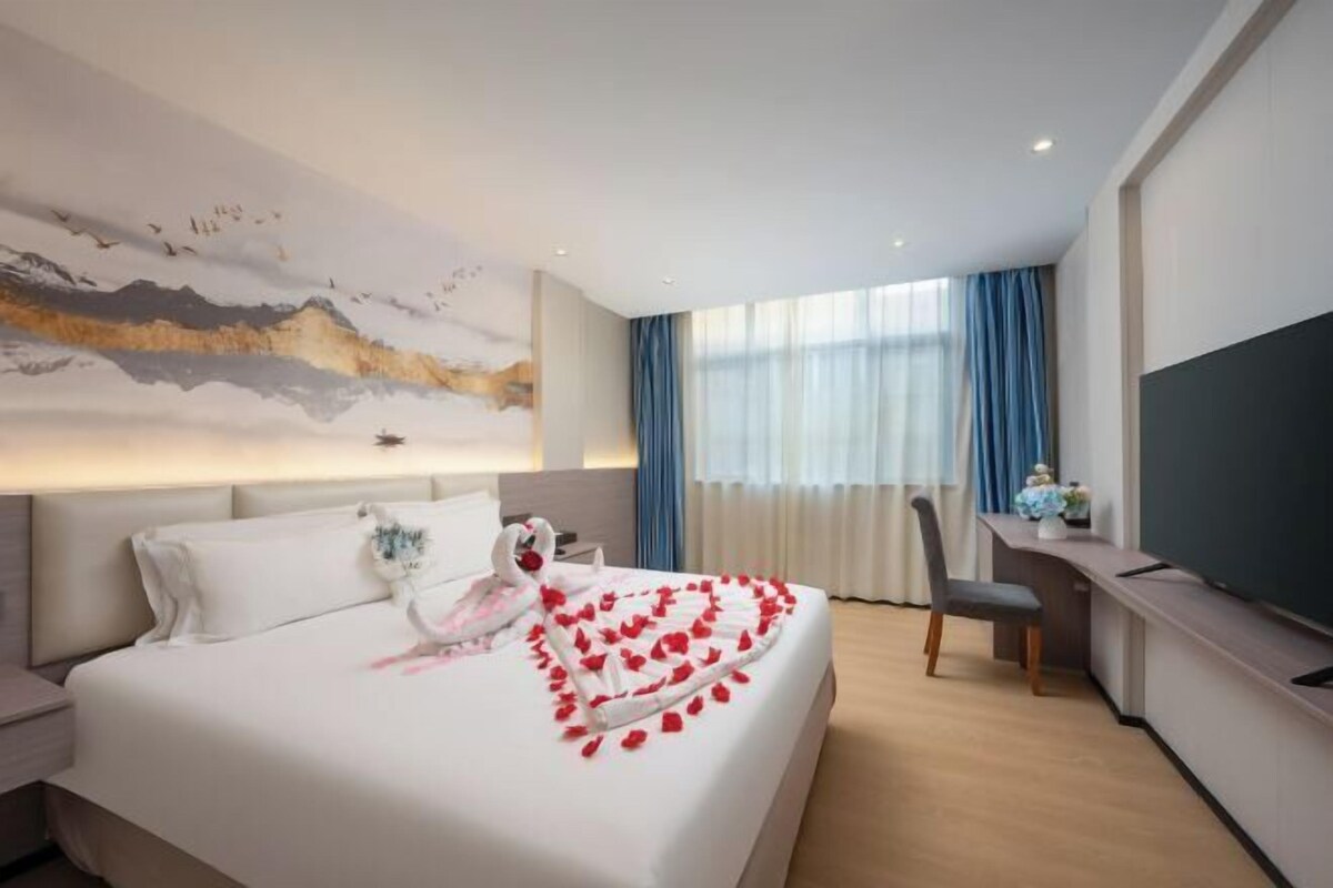 Ein Hotelzimmer mit Bett, Schreibtisch, Stuhl, Fernseher und einem großen Gemälde an der Wand.
