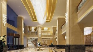 Een ruime lobby met een weelderige kroonluchter, marmeren vloeren en klassieke architecturale details.