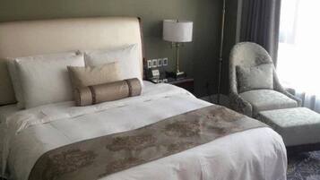 Una habitación de hotel con una cama grande, una silla, una mesita de noche y una lámpara.