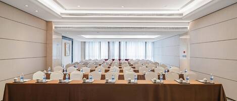 A conference room with a long table, chairs, water bottles, and teapots.