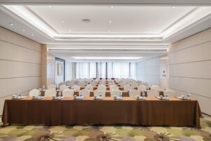Un salón de conferencias con una larga mesa, sillas, botellas de agua y teteras.
