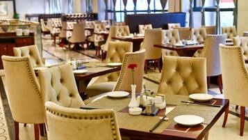 Un restaurante con varias mesas y sillas, algunas con centros de mesa florales.