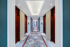 A hotel corridor with a patterned carpet, wooden doors, and a ceiling light. - Welkin Hotel (Lishui)