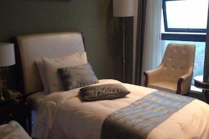Una habitación de hotel con cama, una silla, una lámpara y ventana.