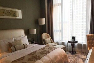 Una habitación de hotel con una cama grande, una silla, una mesita y una lámpara.